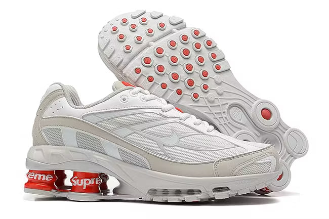 Nike-skor i vitt och orange med Supreme-märke.