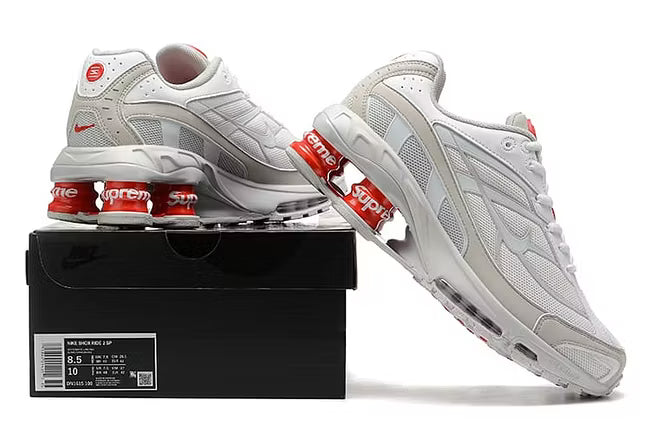 Nike-skor i vitt och orange med Supreme-märke.